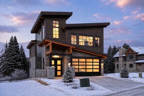 A modern two-story house with a garage, stone foundation, and wooden exterior. - Riverwalk Luxury Home | Hot Tub + Fireplace | Walk to Trails (Winter Park)