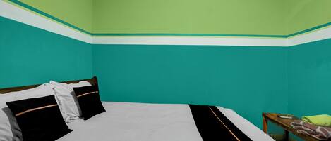 A room with teal walls, a bed with black and white bedding, and a wooden nightstand with a towel.