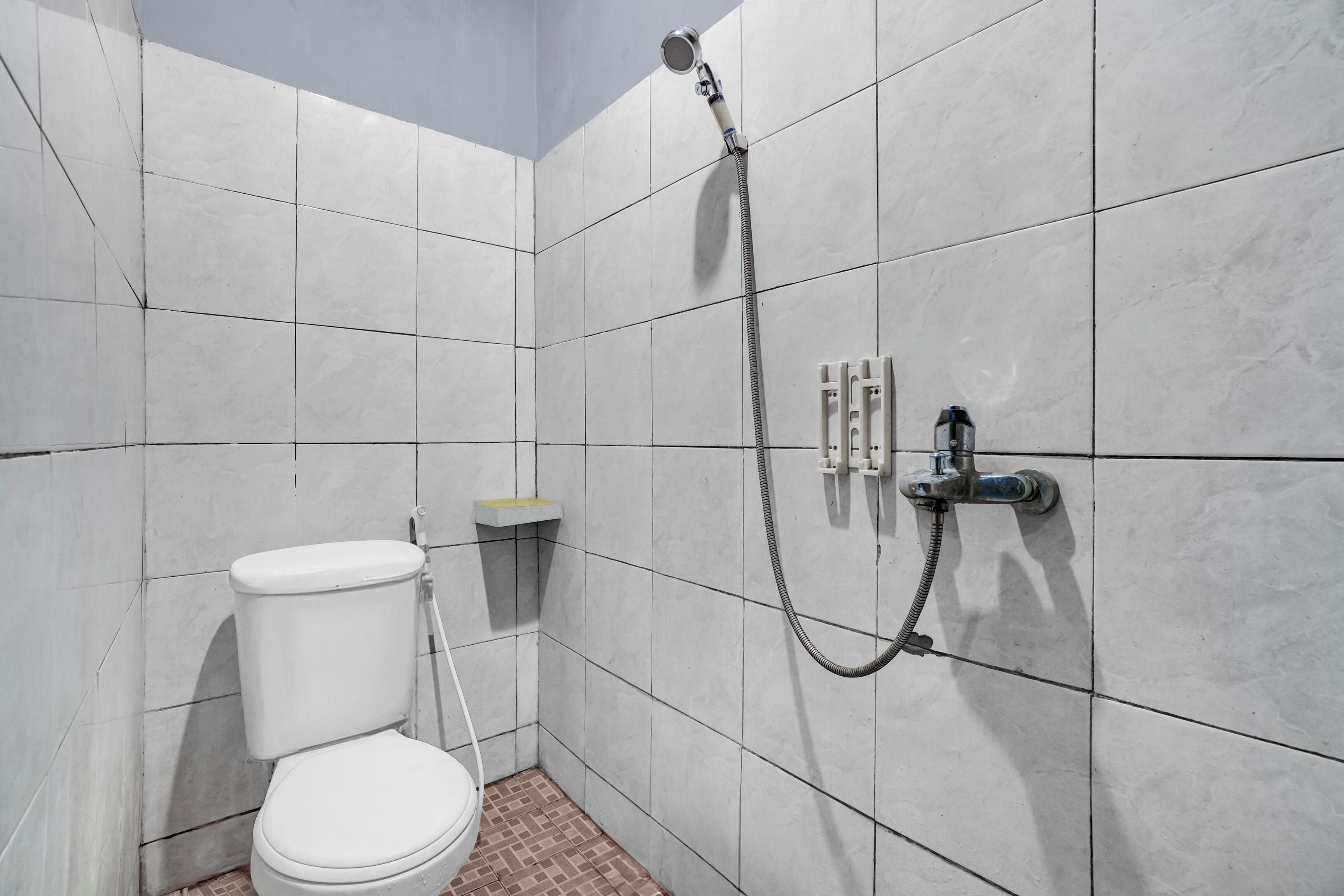 A small, tiled bathroom with a toilet, a shower, and a sink.