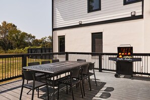 Eine Terrasse mit Tisch und Stühlen, einem Grill und einem weißen Gebäude im Hintergrund.