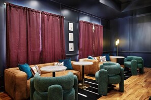 Ein Zimmer mit einer Couch, zwei runden Tischen und grünen Stühlen.