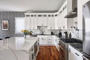 A modern kitchen with white cabinets, a marble countertop, and a central island.
