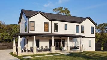 A two-story house with a covered porch, a brick foundation, and a well-maintained lawn.