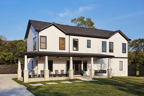 A two-story house with a covered porch, a brick foundation, and a well-maintained lawn.