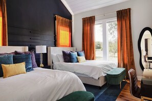 Ein Hotelzimmer mit zwei Betten, einem Schreibtisch, einem Spiegel und Blick ins Freie.