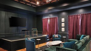 Een moderne lounge met een podium, zitplaatsen en kunstwerken aan de wanden.