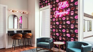 Een moderne badkamer met een wastafel, twee barstoelen, een ronde tafel, en een neonbord met de tekst 'Hello Gorgeous' op de muur.