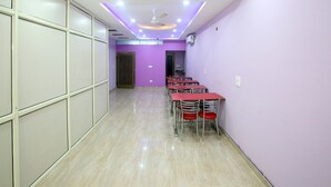 Una sala conferenze con soffitto alto, illuminazione a incasso e una fila di tavoli con sedie.