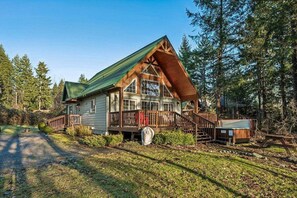 A cabin with a steeply pitched roof, large windows, and a porch with a railing. - Packwood Landing | Hot Tub • Pet-Friendly (Packwood)