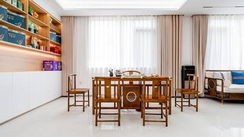 Un coin repas avec une table et des chaises en bois, une bibliothèque contenant divers objets et un canapé agrémenté d’un coussin décoratif.