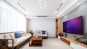 Egy modern nappali, amelyben egy kanapé-garnitúra, egy dohányasztal és egy falra szerelt, síkképernyős televízió található.