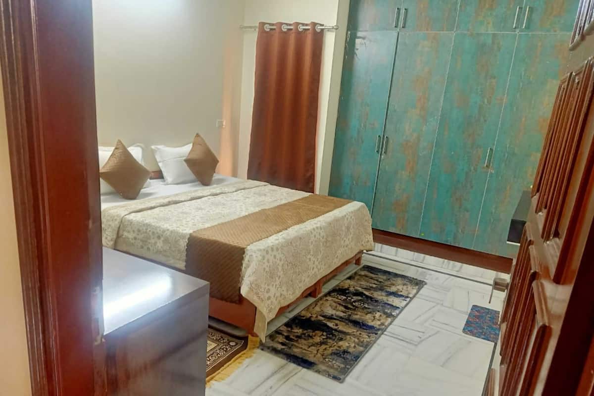 Un dormitorio con cama, armario y baño visible a través de una puerta abierta.