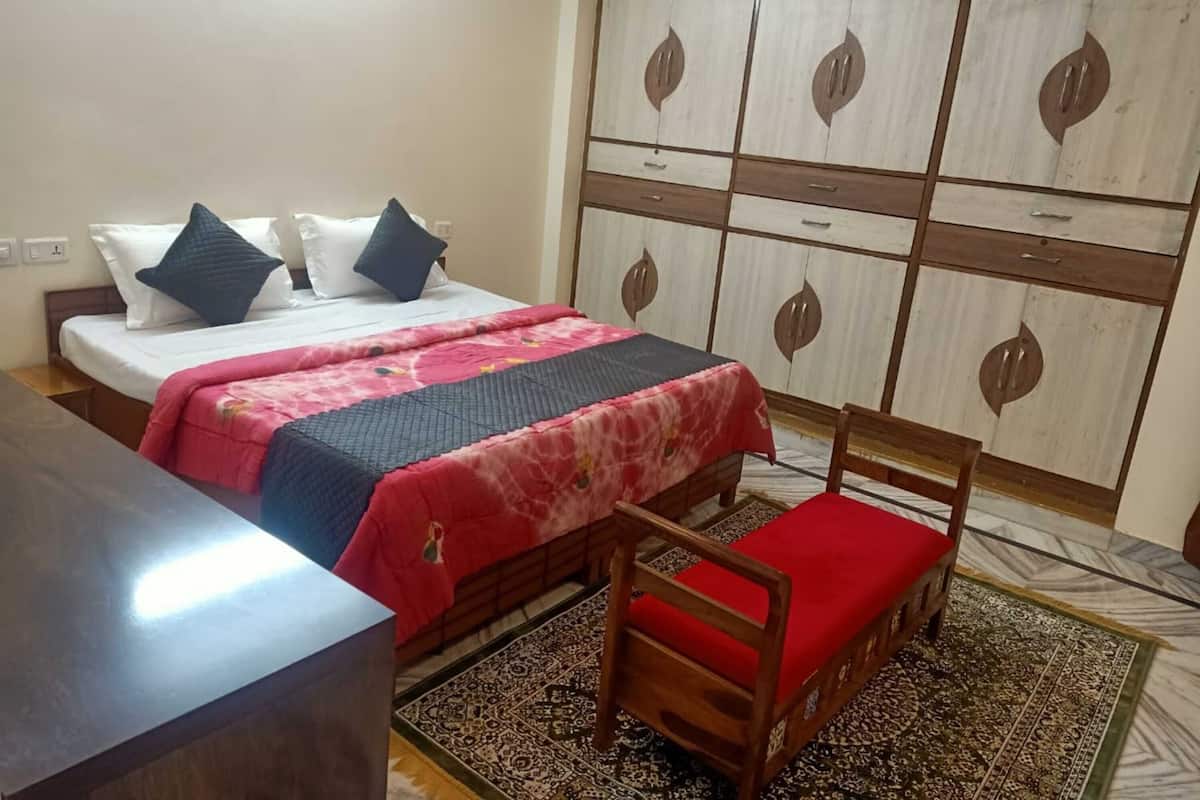 Un dormitorio con una cama, una silla de madera, un armario y un escritorio.