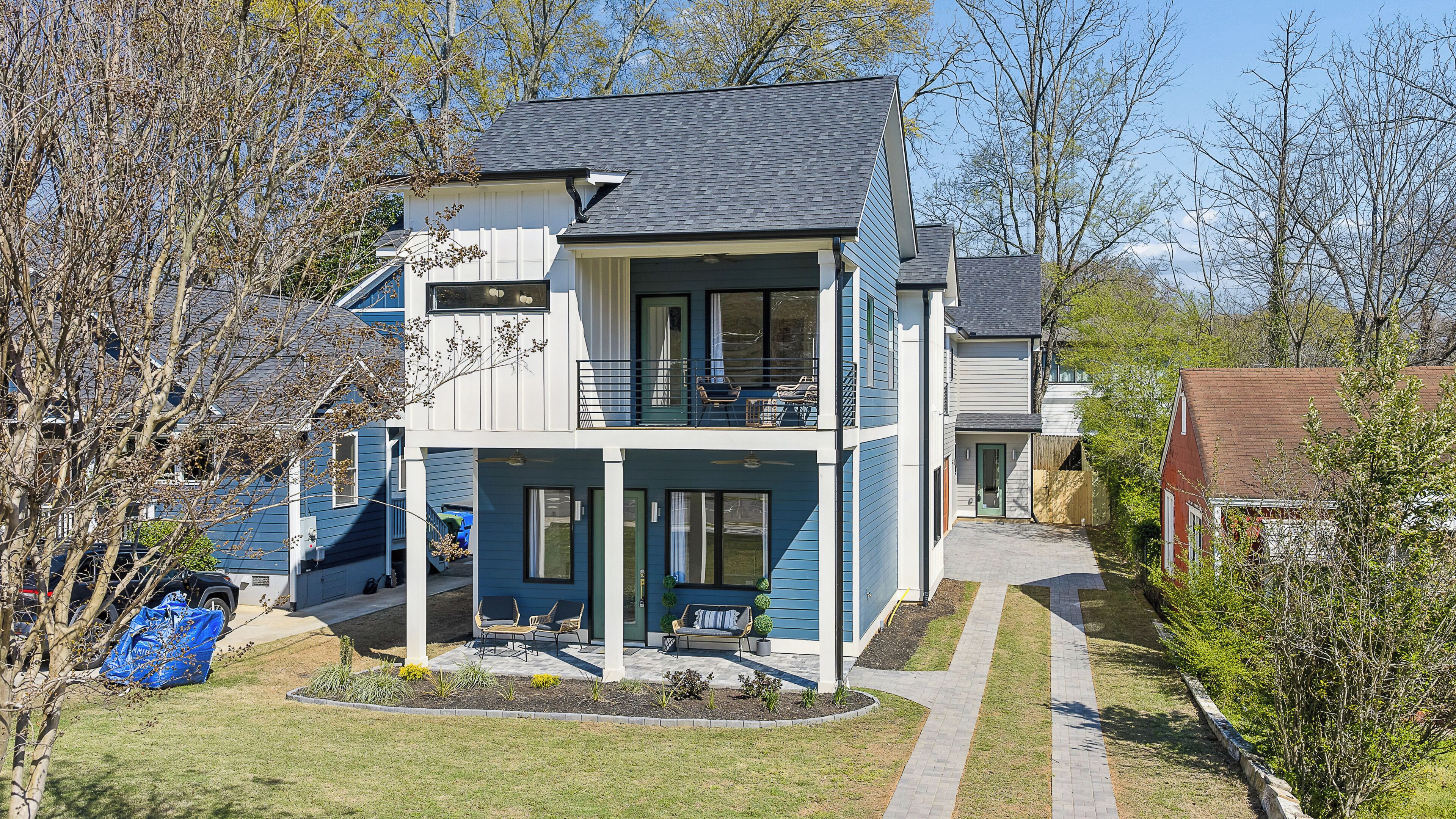 A two-story house with a balcony, a driveway, and a small garden area.