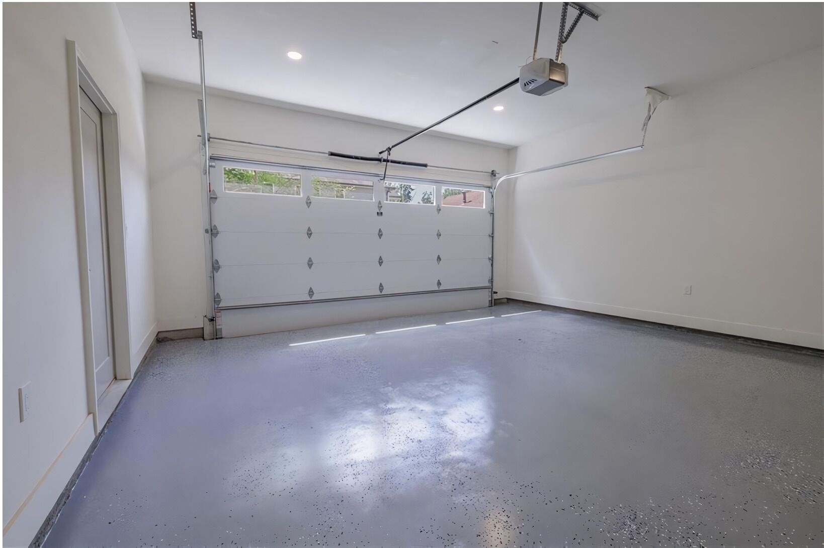 Un garaje limpio y vacío, con piso de concreto y puerta blanca.
