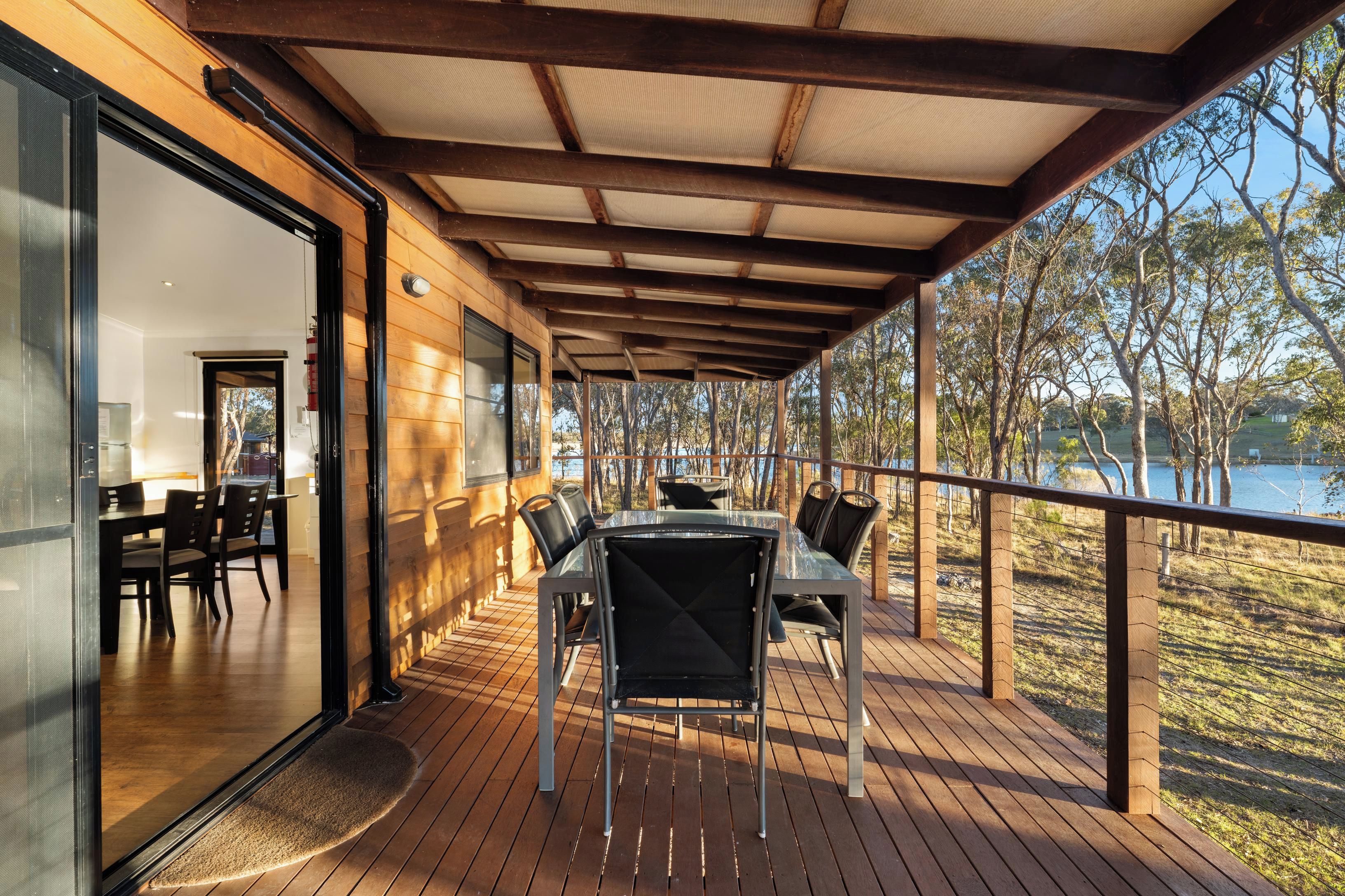 An outdoor deck with a table and chairs, overlooking a body of water and trees.