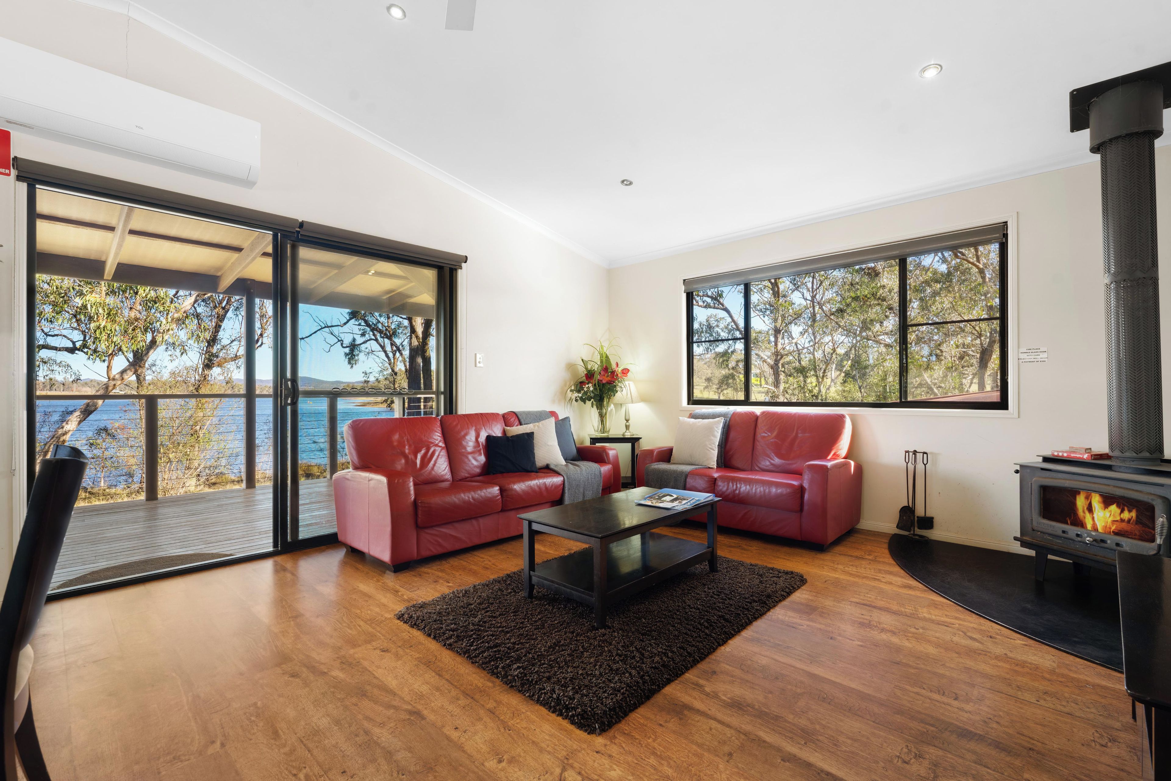 A modern living room with a fireplace, leather sofas, a coffee table, and a view of the outdoors.