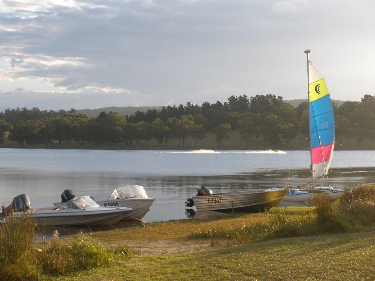 A lakeside scene with boats and a sailboat.