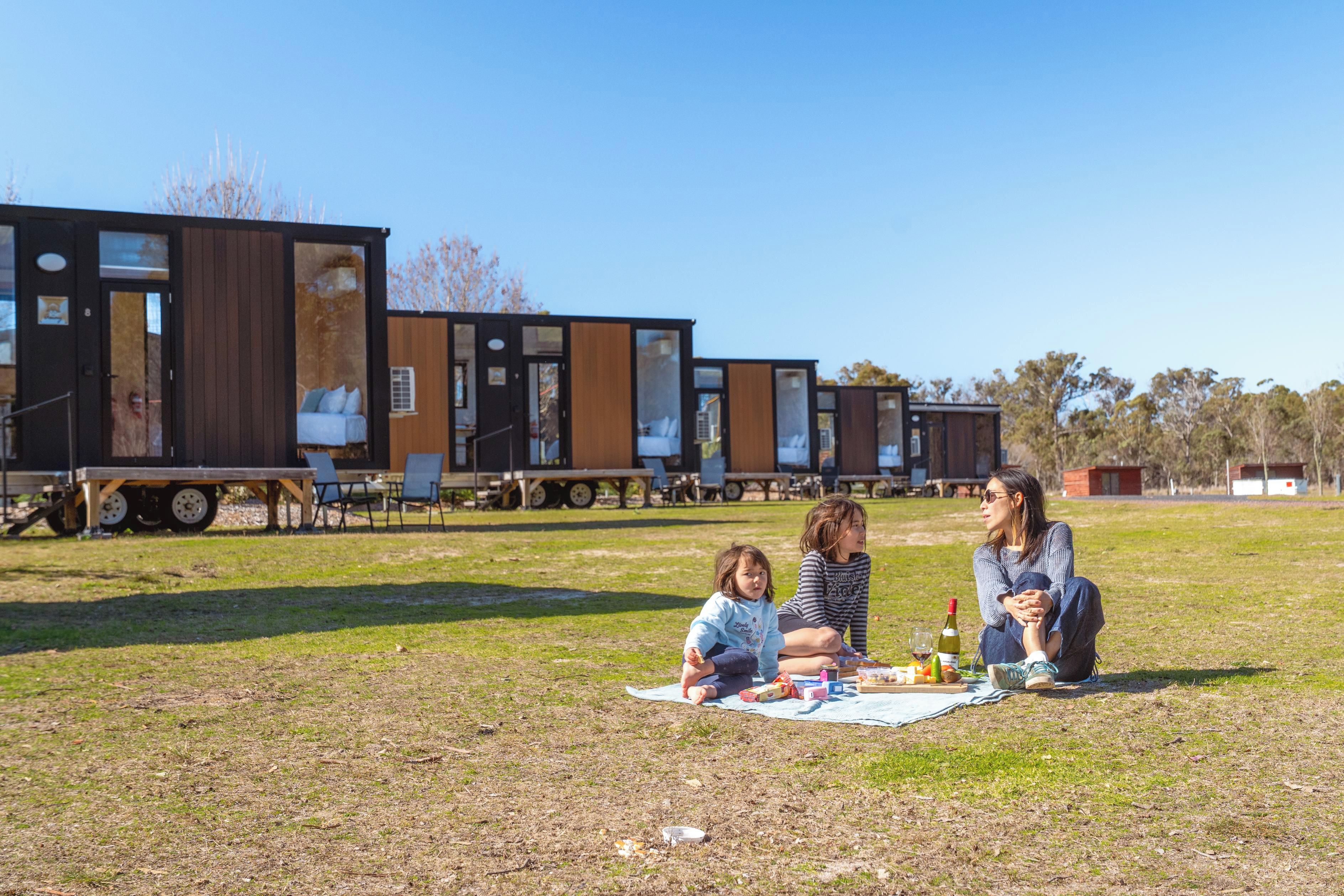 Un camping con vehículos recreativos y un área de picnic con gente y comida.