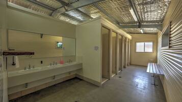 A restroom with multiple sinks, a large mirror, and a bench.