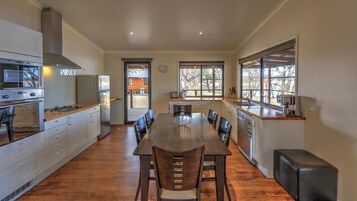A modern kitchen with a central island, stainless steel appliances, and large windows.