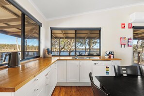 Una cocina moderna con armarios blancos, encimera de madera y vistas a un lago.