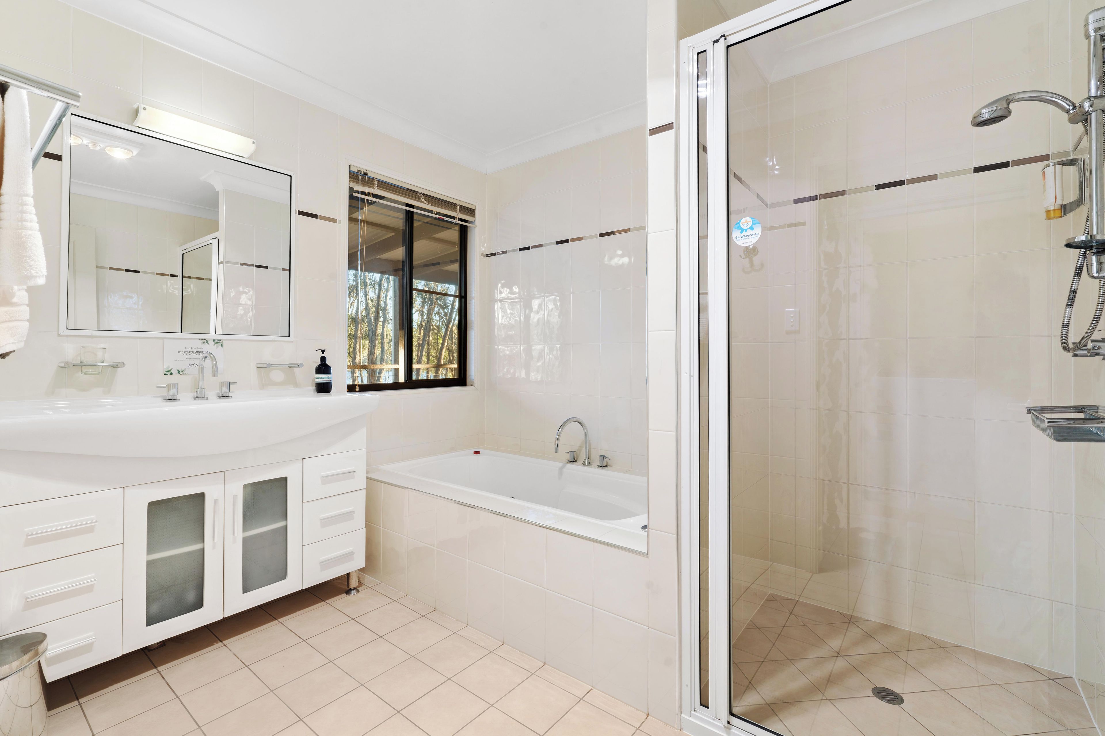 A modern bathroom with a large mirror, a bathtub, and a shower area.
