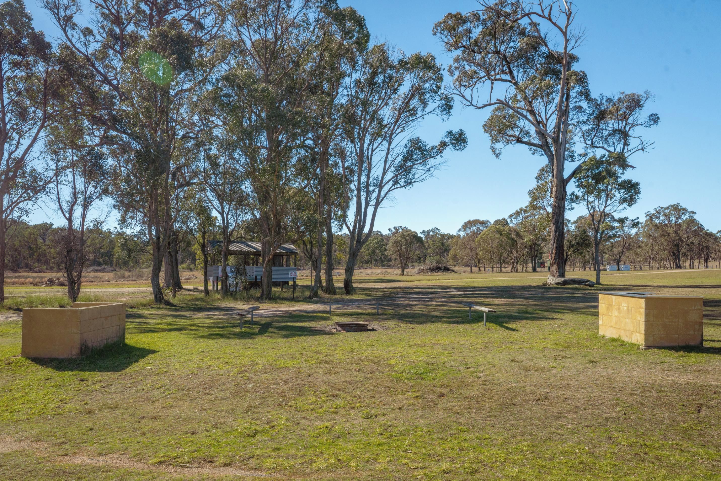 A park with picnic tables, a small shelter, and a grassy field.