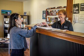 A reception desk with a person handing over a card to another person. - Tiny Away Escape at Granite Belt (Stanthorpe)