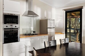 A modern kitchen with a built-in oven, a stainless steel range, and a refrigerator. - Tiny Away Escape at Granite Belt (Stanthorpe)
