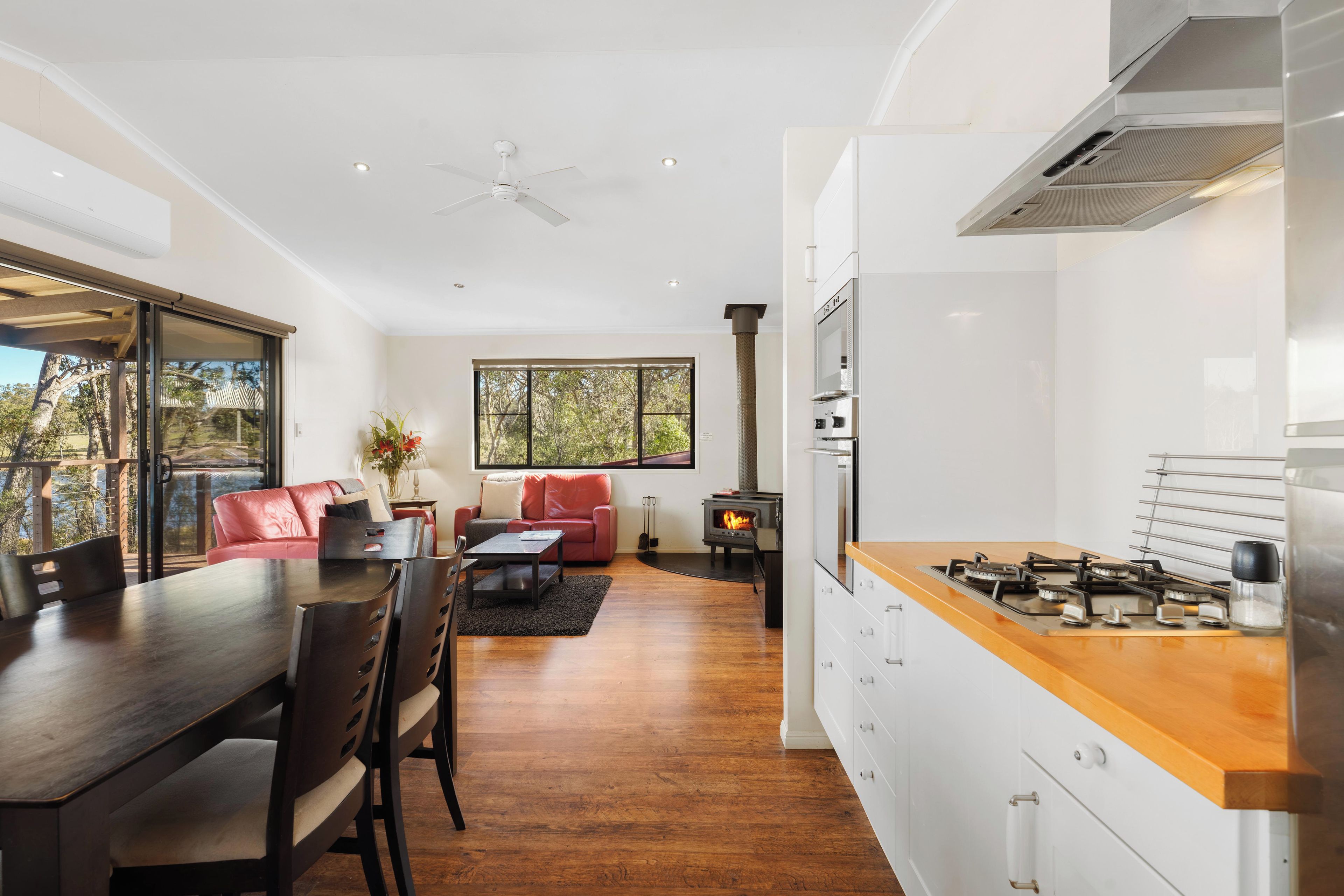 Een moderne keuken met een centraal eiland, een zithoek met tafel en stoelen, en een woongedeelte met een bank en een open haard.