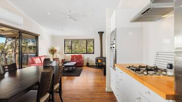 Een moderne keuken met een centraal eiland, een zithoek met tafel en stoelen, en een woongedeelte met een bank en een open haard.