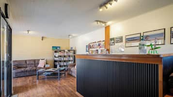 A reception area with a wooden counter, a bookshelf, a sofa, and a coffee table.