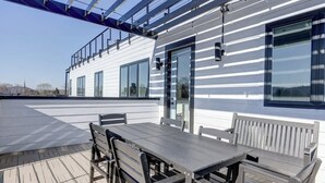 A rooftop terrace with a table and chairs, a glass door, and a view of the surrounding landscape. - Pet-Friendly in Belmont near UVA & Downtown - #311 (Charlottesville)