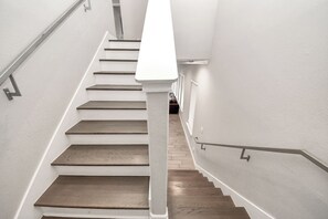 Eine Treppe mit weißen Wänden, Holzhinweisstufen und einem weißen Geländer.