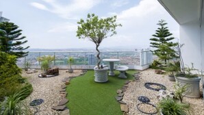 A rooftop garden with a view of the city, featuring a central tree, potted plants, and a seating area. - Almendra I Spacious 1 Bedroom With Balcony (Panama City)