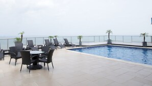 A rooftop pool area with lounge chairs and a table, overlooking a body of water. - Almendra I Spacious 1 Bedroom With Balcony (Panama City)