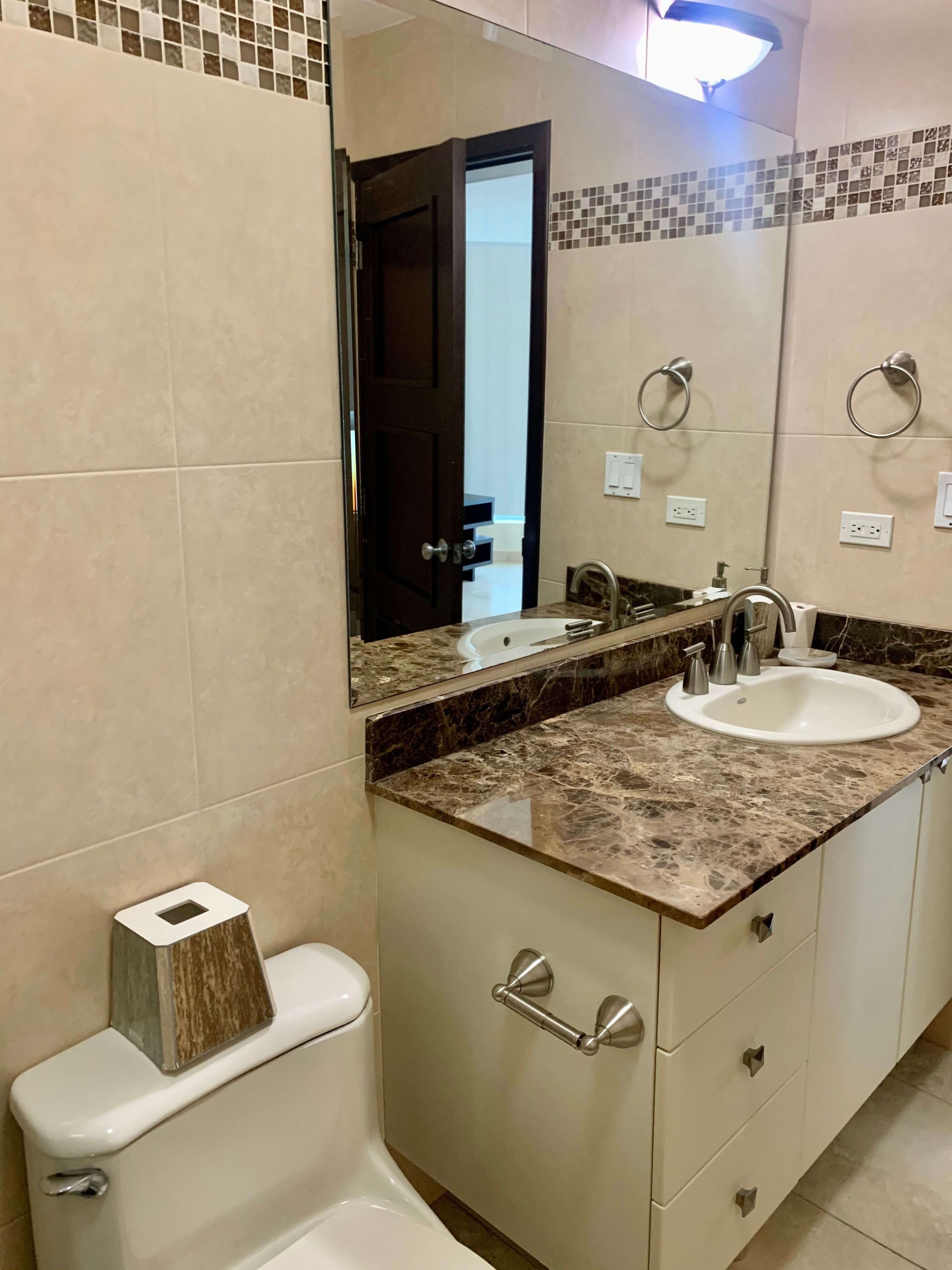 Ein Badezimmer mit Toilette, Waschbecken, Spiegel und Schrank.