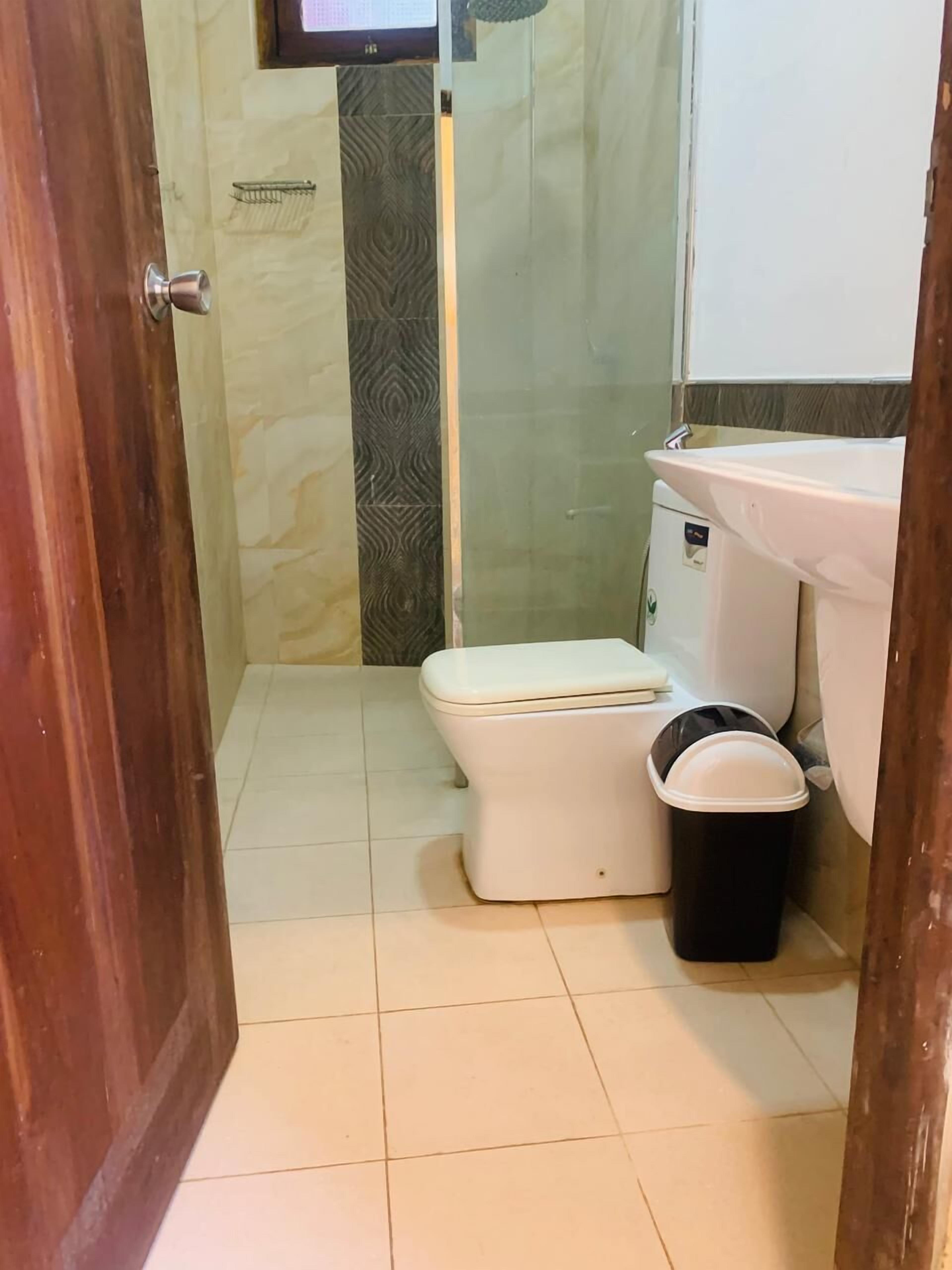 A small bathroom with a toilet, a trash bin, and a sink.