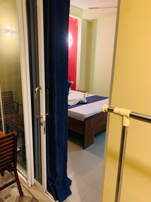 A hotel room with a bed, a chair, and a sliding glass door. - Deergayu Homestay  (Mirissa)