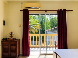 A room with a sliding glass door leading to a balcony, a wooden cabinet, and a bed. - Deergayu Homestay  (Mirissa)
