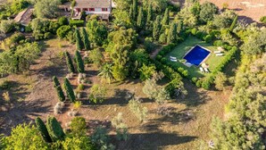 Vista aérea de una propiedad con piscina, edificio de techo rojo y vegetación circundante.
