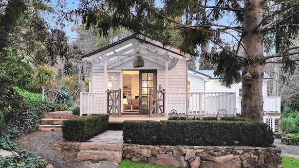 Un accogliente cottage con portico coperto, gradini in pietra e un giardino curato.