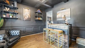A modern bar area with stools, a counter, and shelves with various items.