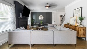 A modern living room with a sectional sofa, a fireplace, and a ceiling fan.