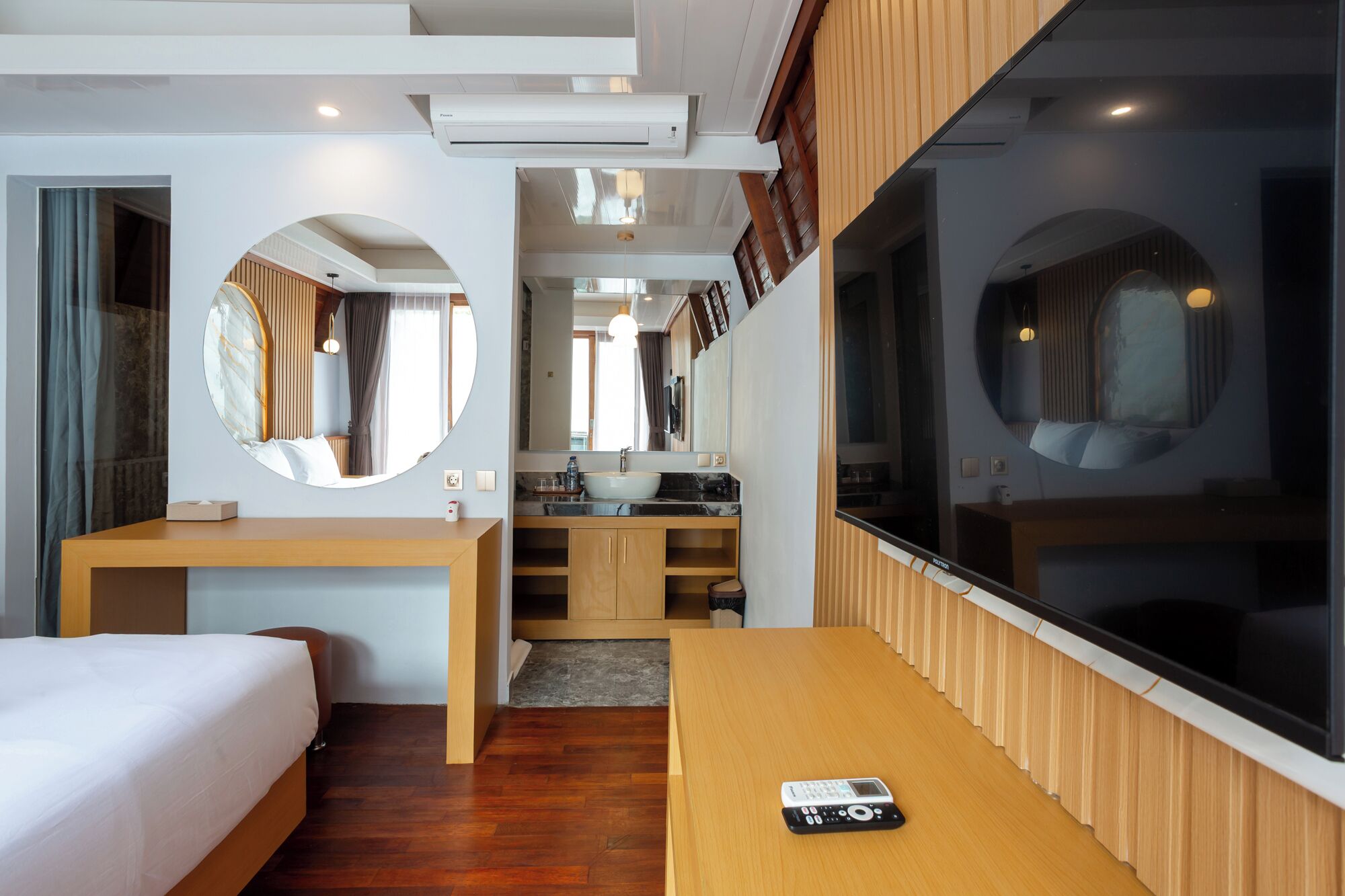 Una habitación de hotel moderna con cama, escritorio, baño y un ventanal grande.