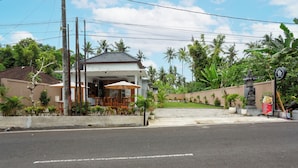 A restaurant with outdoor seating, a paved entrance, and a stone pathway leading to the entrance. - Merta Luwih villa (Tabanan)
