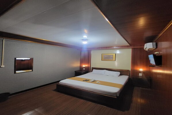 A hotel room with a bed, bedside table, lamp, and a television on the wall. - OYO 95110 Eksklusif Gueshouse Syariah (Kauman)