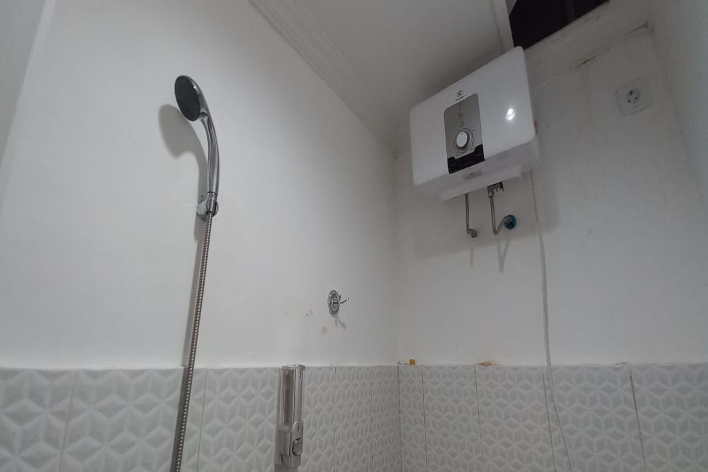 Ducha con cabezal de ducha de mano y panel de control en la pared.