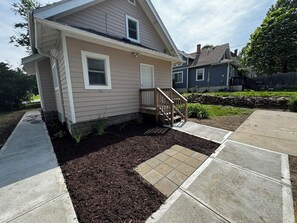 A residential house with a front porch, a small garden area with mulch, and a paved walkway. - Historic Omaha Home overlooks Park. 3BR. Free Parking. 2.7 miles to Schwab Field (Omaha)
